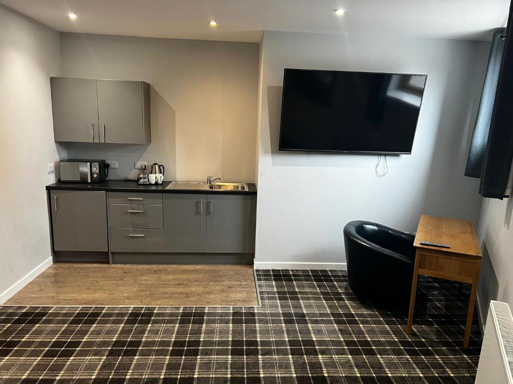 a room with a kitchen with a tv on the wall at Crown Hotel & Bar in Inverness