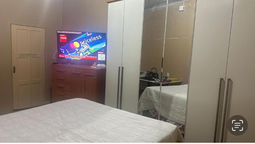um quarto com uma televisão, uma cama e um espelho em Casa confortável e bem localizada em Macapá