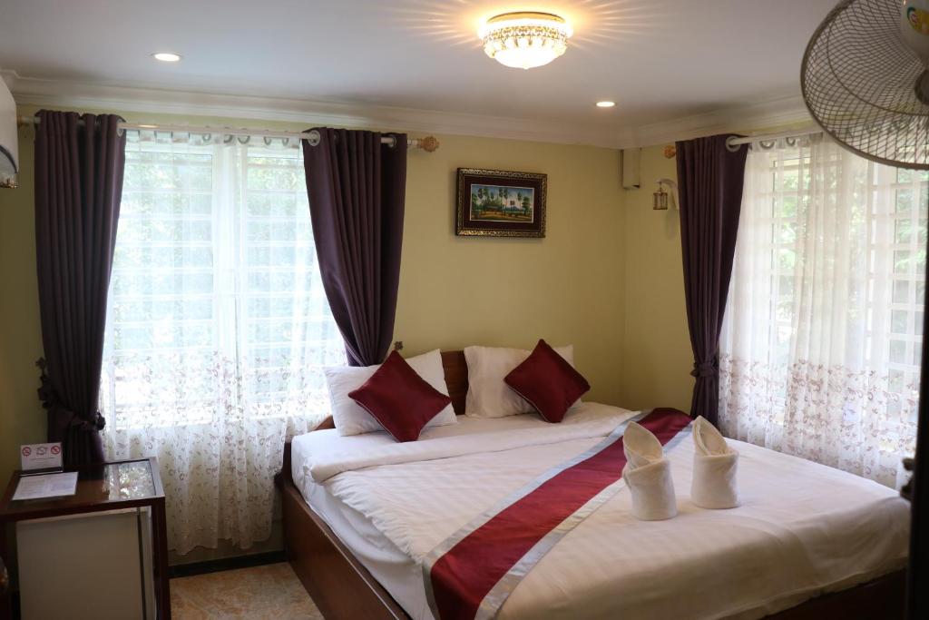 a bedroom with a bed with white sheets and red pillows at AHHA Boutique Kampot in Kampot