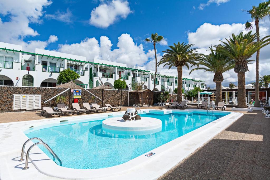 卡门港Guasimeta Duplex - Pool & Balcony的有棕榈树的游泳池和一栋建筑