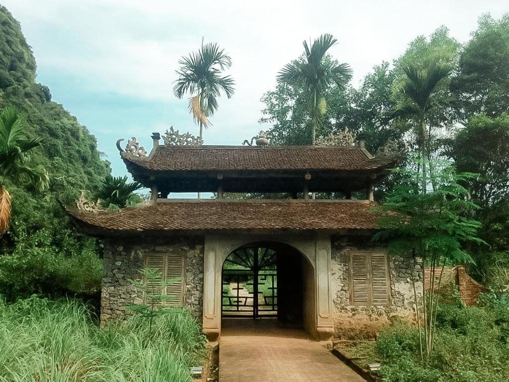 an entrance to a building with a gate and palm trees at Ancient House Cat Ba in Hai Phong