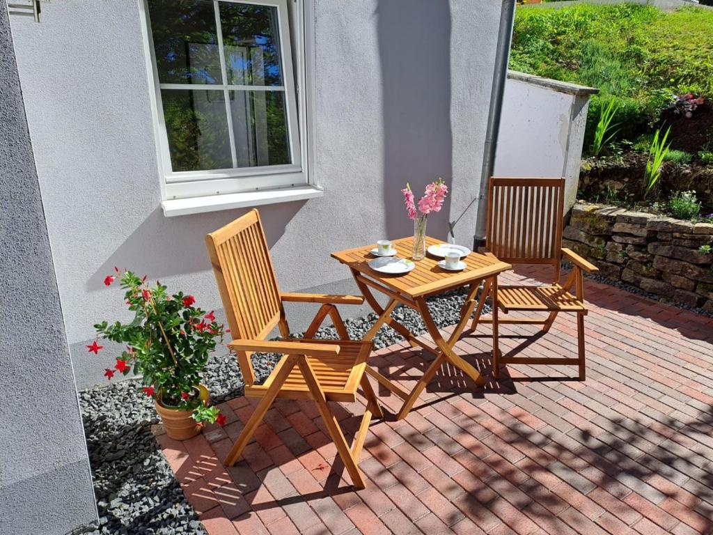 einen Holztisch und zwei Stühle auf einer Terrasse in der Unterkunft Ferienwohnung Waldeule in Bad Kissingen