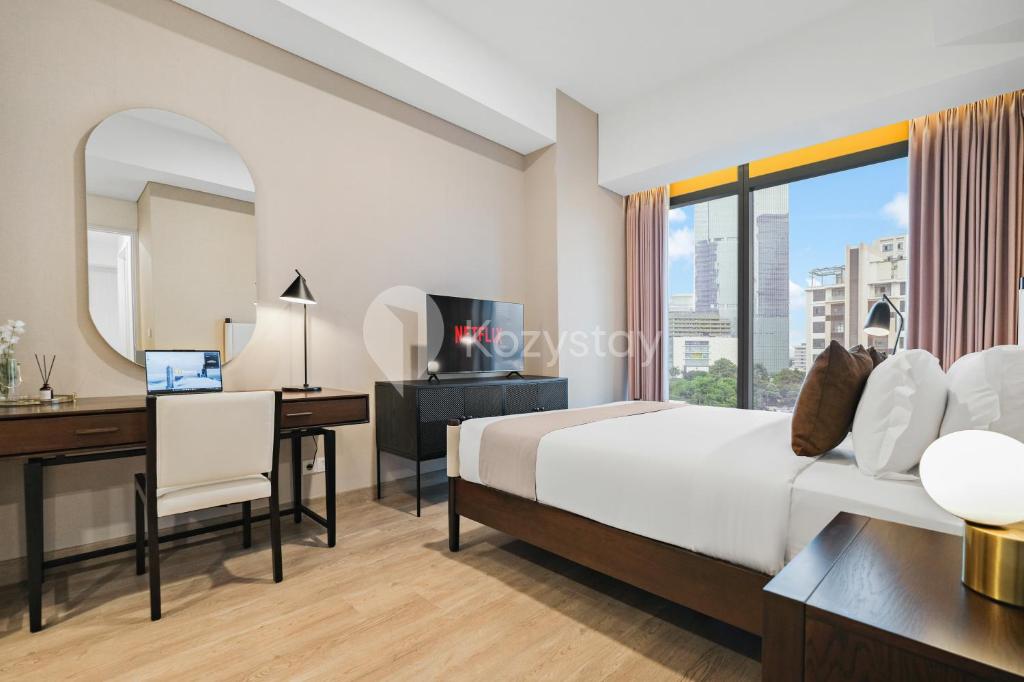 ein Hotelzimmer mit einem Bett, einem Schreibtisch und einem Spiegel in der Unterkunft Thames by Kozystay - 2BR - Near GI Mall - Thamrin in Jakarta