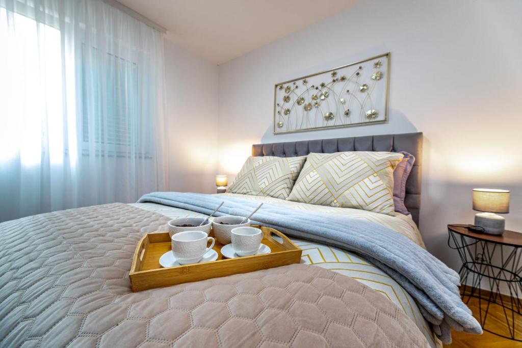 a bed with a tray with two cups on it at Angie in Baška