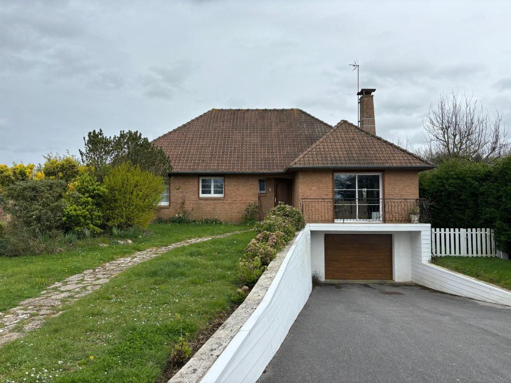 una casa con una valla blanca y un garaje en À l'orée du bois, en Étaples