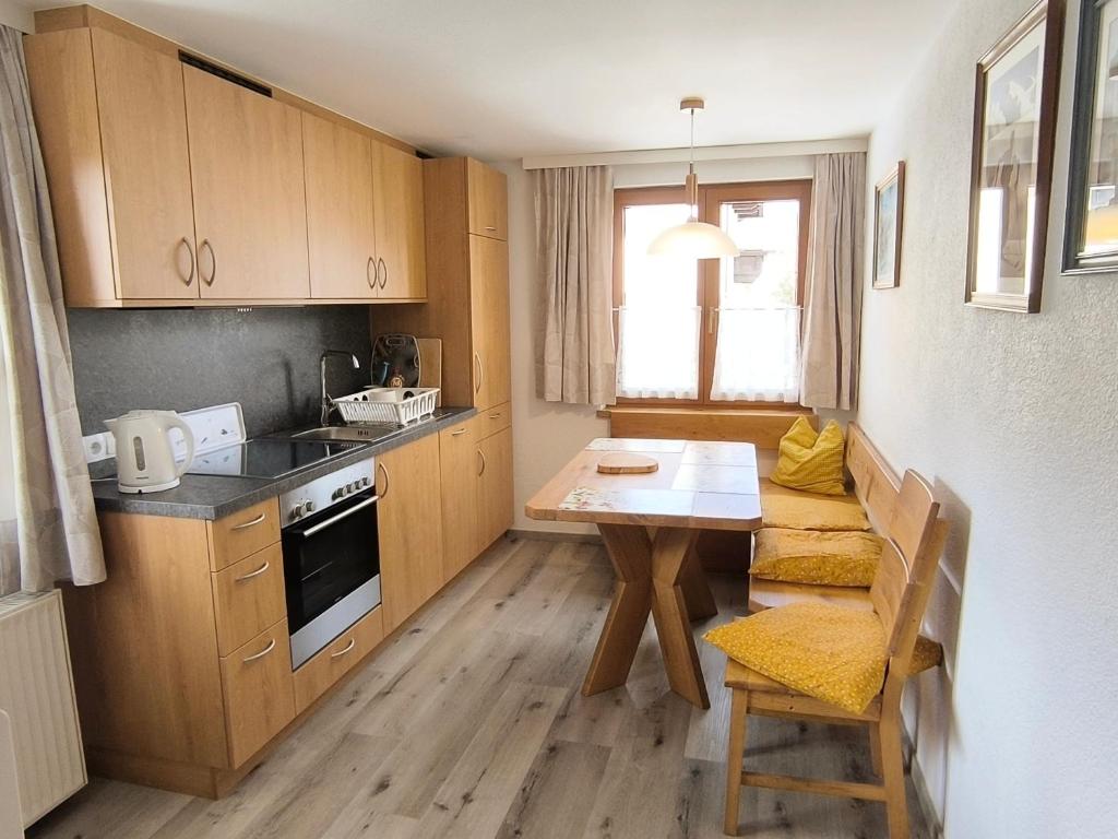une cuisine avec des placards en bois et une table ainsi qu'une salle à manger dans l'établissement Ferienwohnung Spitzmandl, à Innsbruck