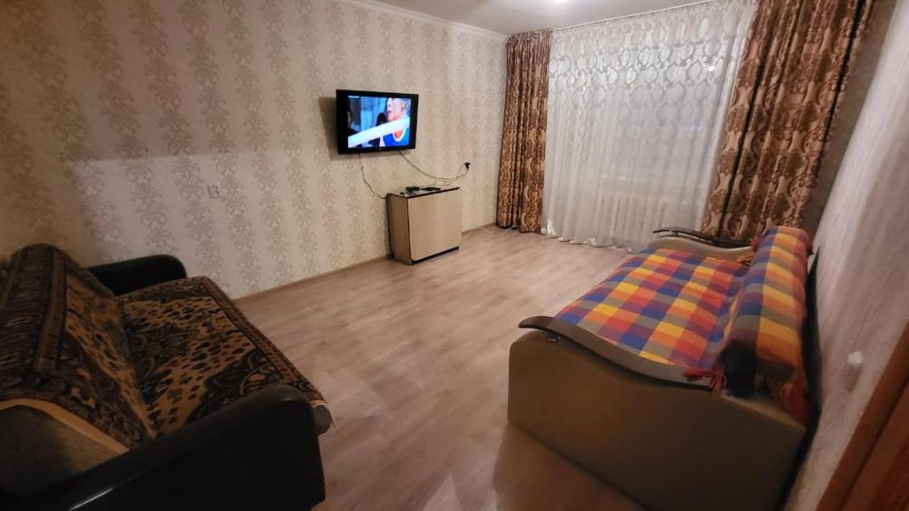 ein Wohnzimmer mit 2 Stühlen und einem TV in der Unterkunft Маринад in Petropawlowsk
