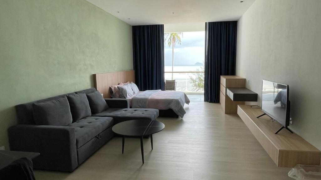ein Wohnzimmer mit einem Sofa, einem Bett und einem TV in der Unterkunft Freedom Flamingos@Roxy Beach in Lundu