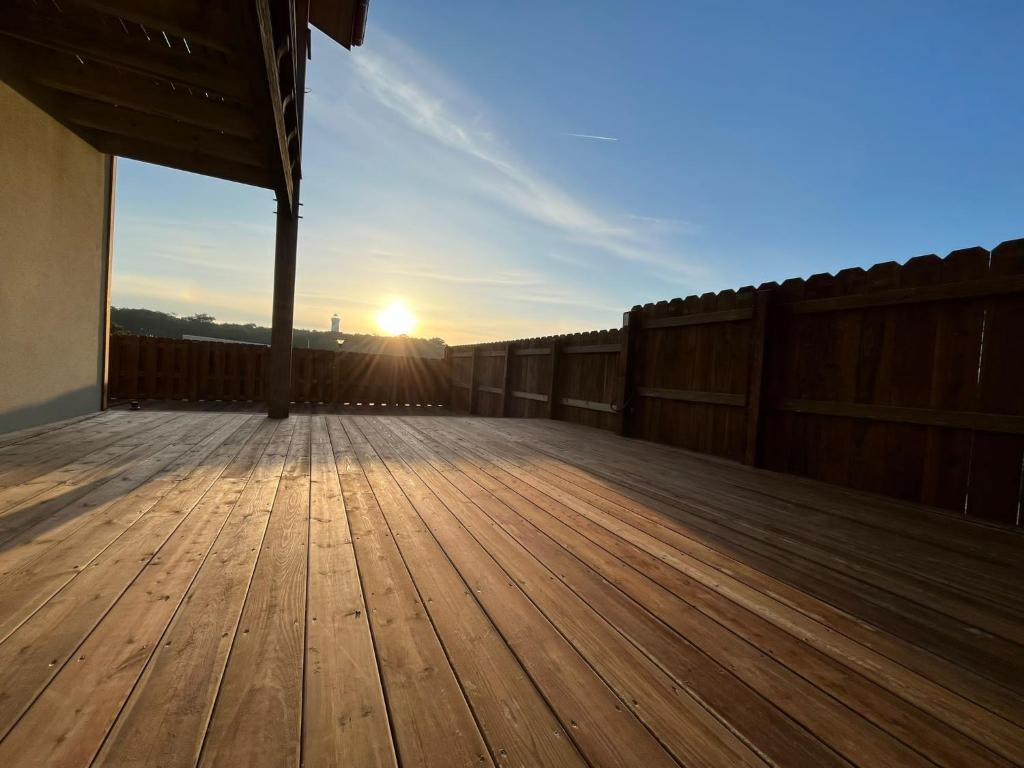 une terrasse en bois avec vue sur le coucher du soleil en arrière-plan dans l'établissement LE DODO LĖ LA, à Saint-Julien-en-Born