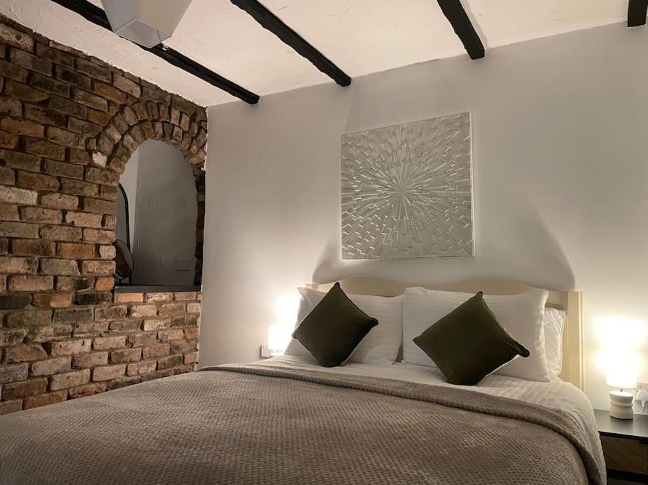 a bedroom with a brick wall and a bed with pillows at Lower Harbour watch in Holyhead
