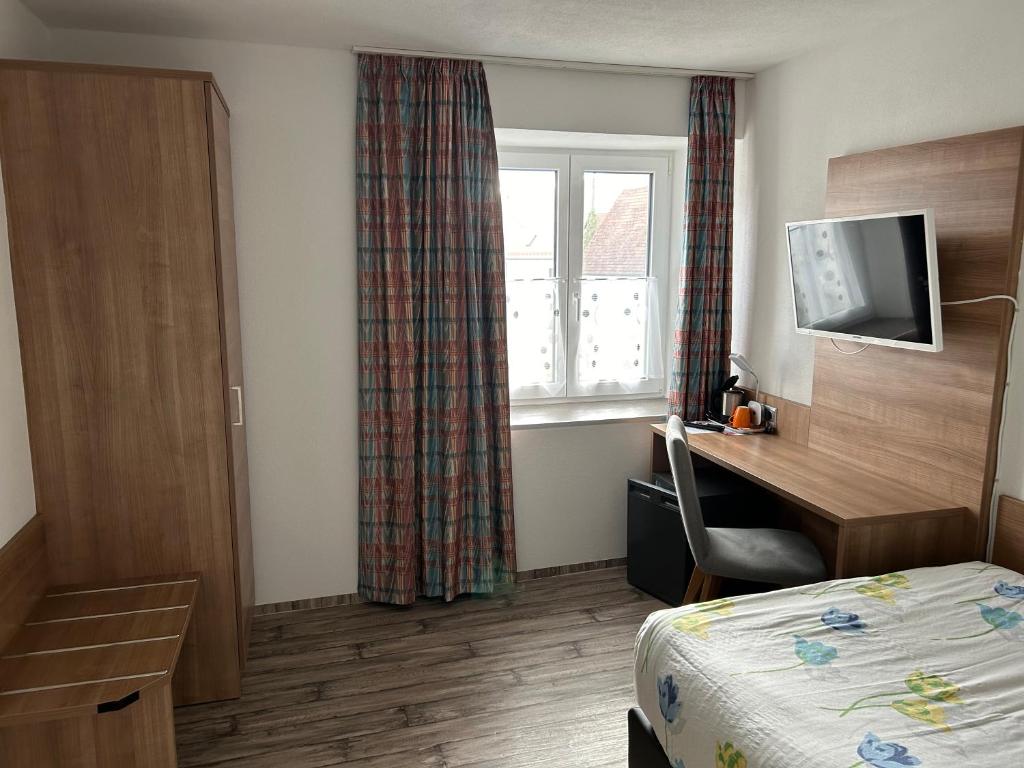 a hotel room with a bed and a desk and a window at Landhotel Müller im Donautal in Tapfheim