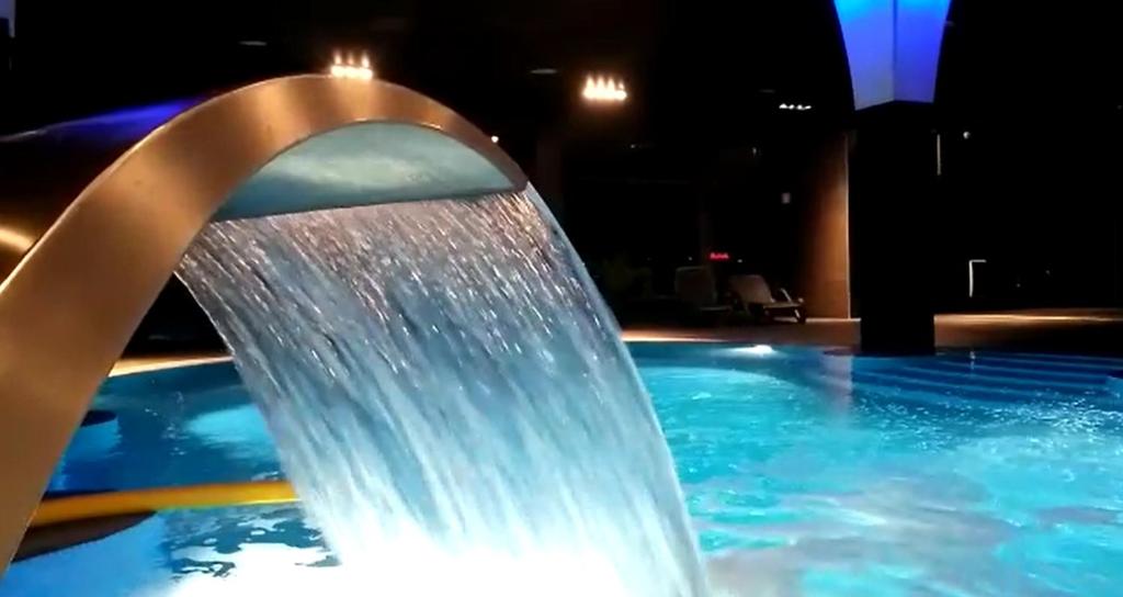 a water fountain in a swimming pool at night at Silver Hotel & Gokart Center in Szczecin