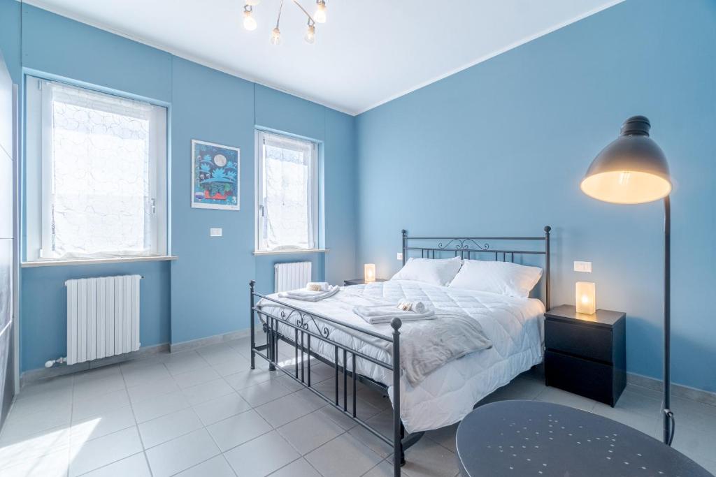 1 dormitorio azul con 1 cama y 2 ventanas en Asti Comentina Railway Functional Flat, en Asti