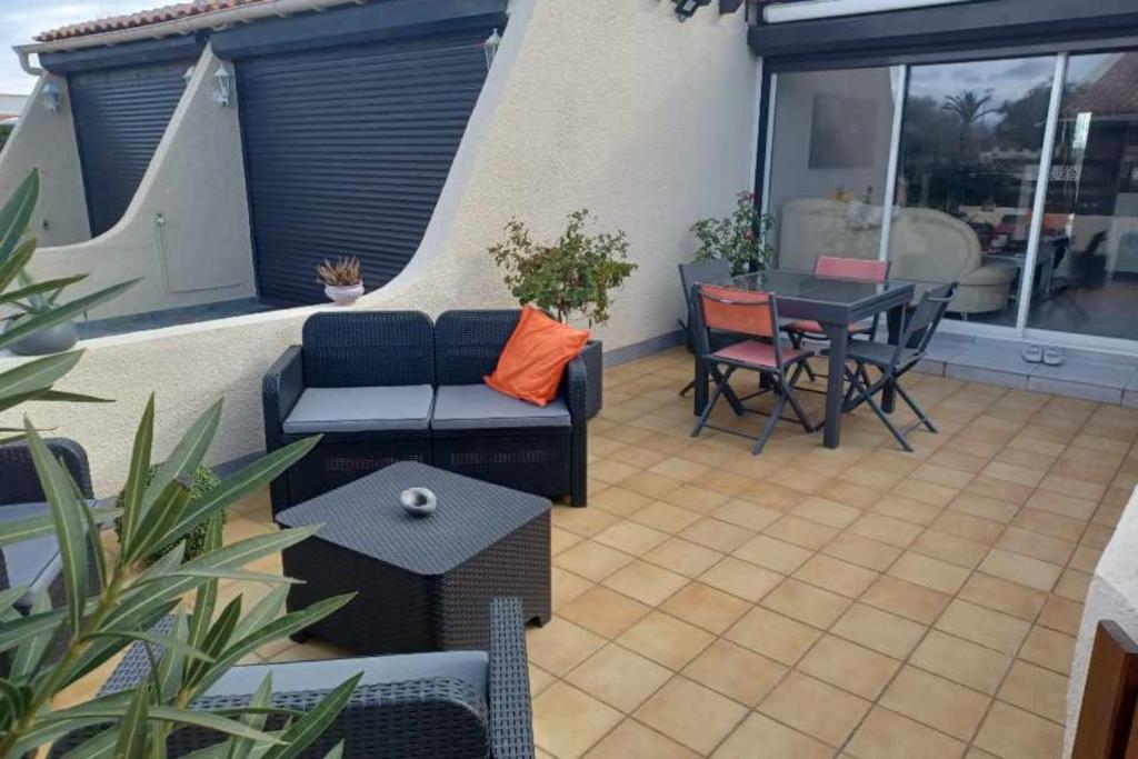 un patio avec un canapé, une table et des chaises dans l'établissement Naturiste Cap d'Agde Villa Héliovillage 3, au Cap d'Agde
