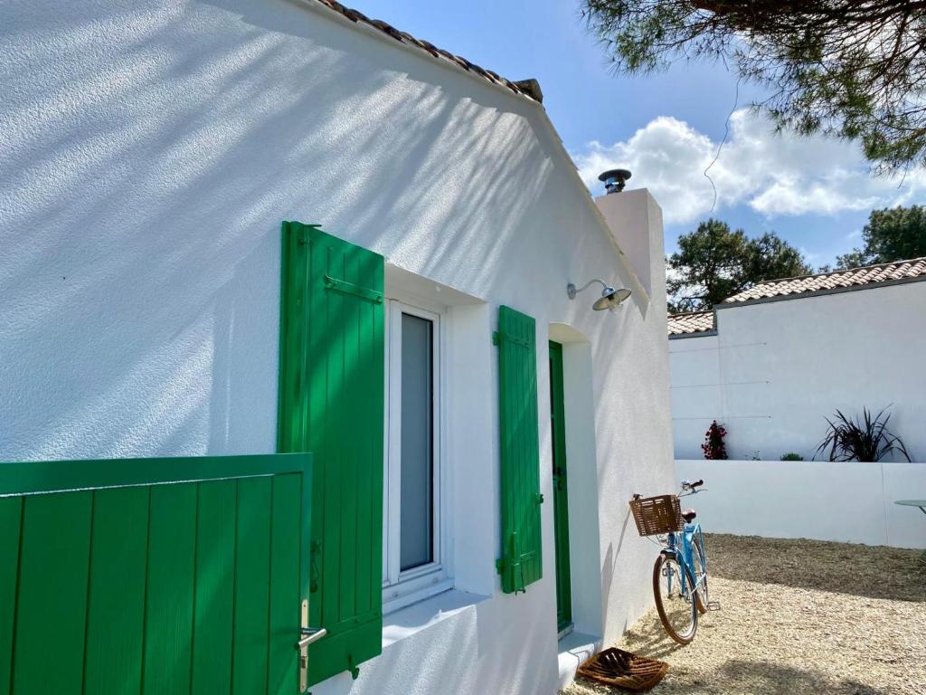 una puerta verde en un edificio blanco con una bicicleta en Calme et tranquillité -Ile de Ré, en Rivedoux-Plage