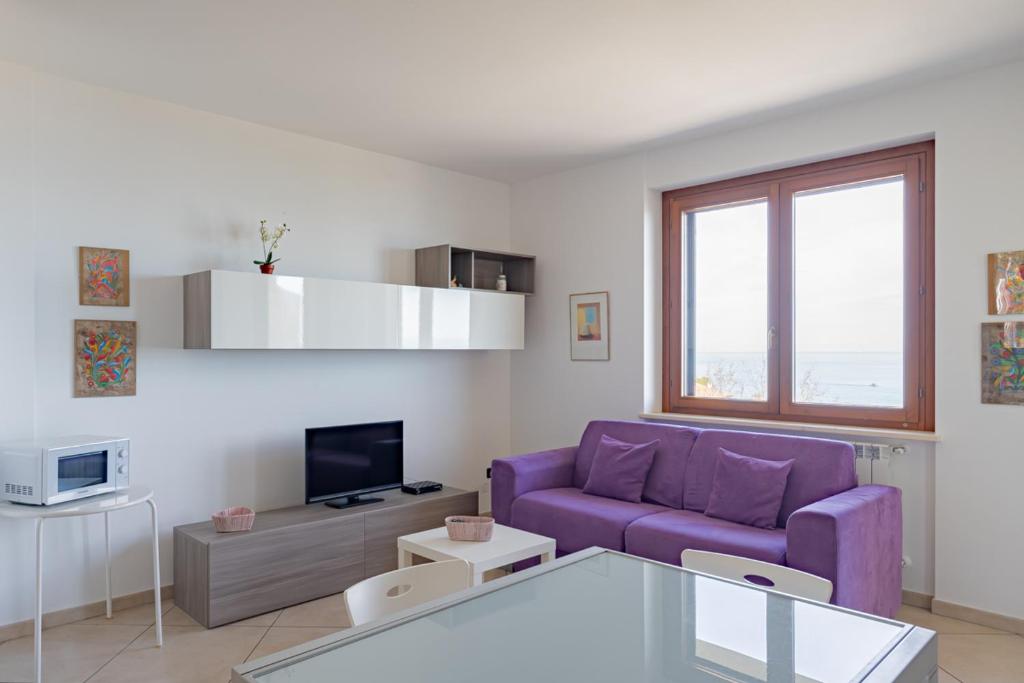 sala de estar con sofá púrpura y TV en Cintioni a mare C 9 - YourPlace Abruzzo, en Marina di San Vito