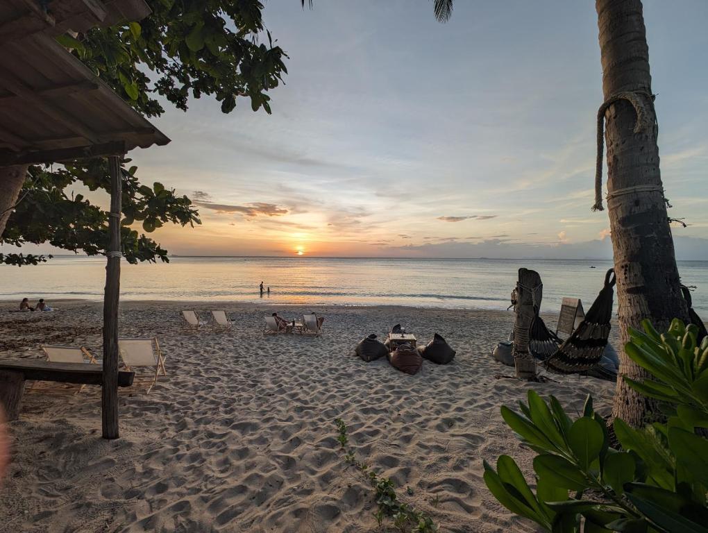 a sunset on a beach with people sitting on the sand at Scandinavian Beach Resort in Ko Lanta