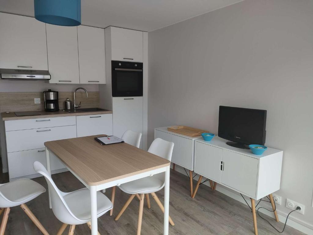 Il comprend une cuisine avec une table et une télévision. dans l'établissement Ref 151 - Appartement T1bis Terrasses de Kerjouanno vue mer, à Arzon