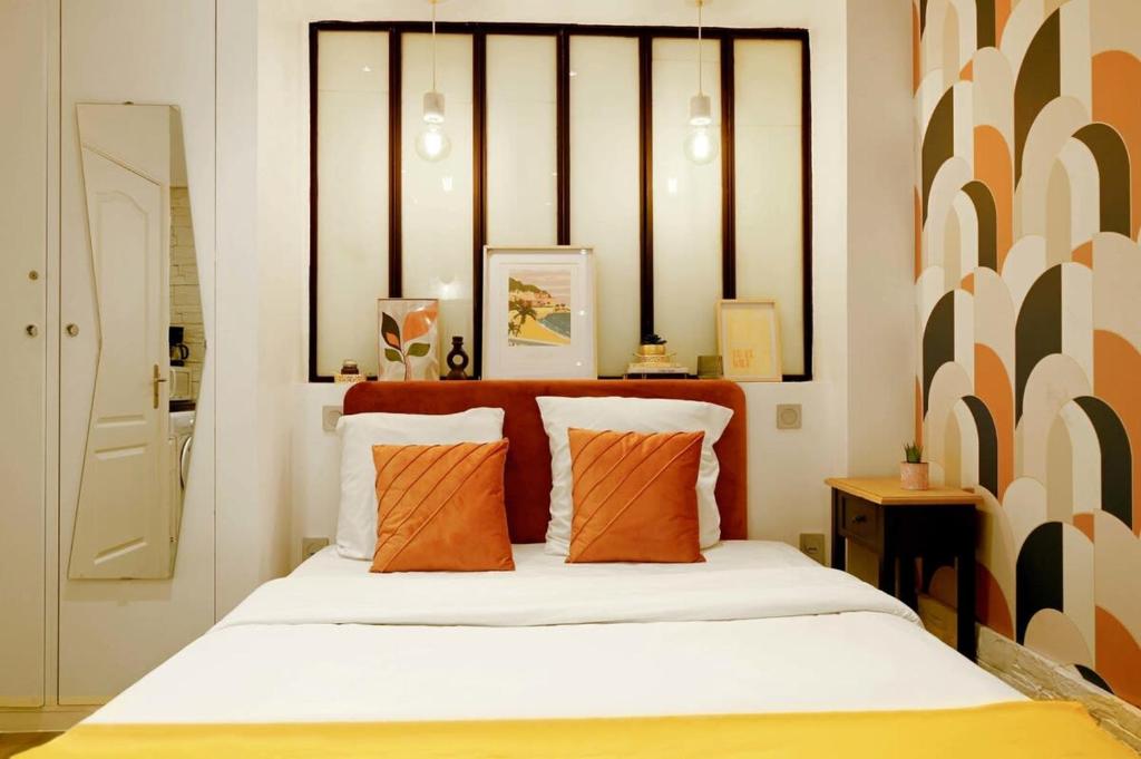 a bedroom with a bed with orange and white pillows at Cosy and modern updated studio in Paris