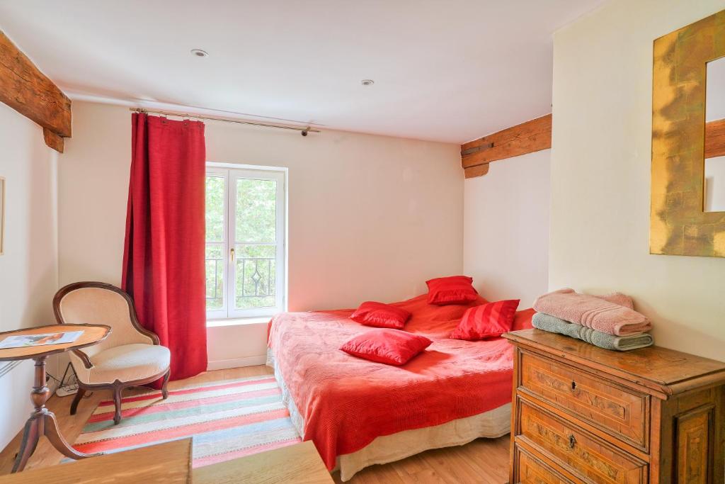 a bedroom with a red bed and a desk and a window at Centre Ahimsa in Verrières-le-Buisson