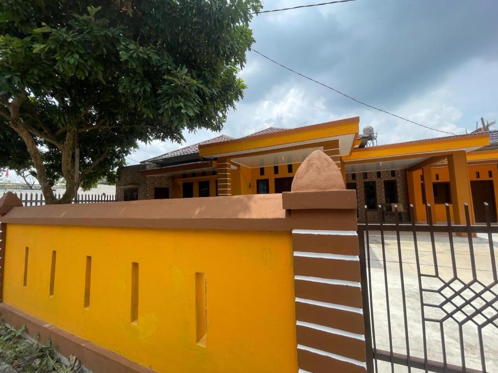 una cerca amarilla frente a una casa en OYO 93866 Neva Guest House Syariah, en Parit