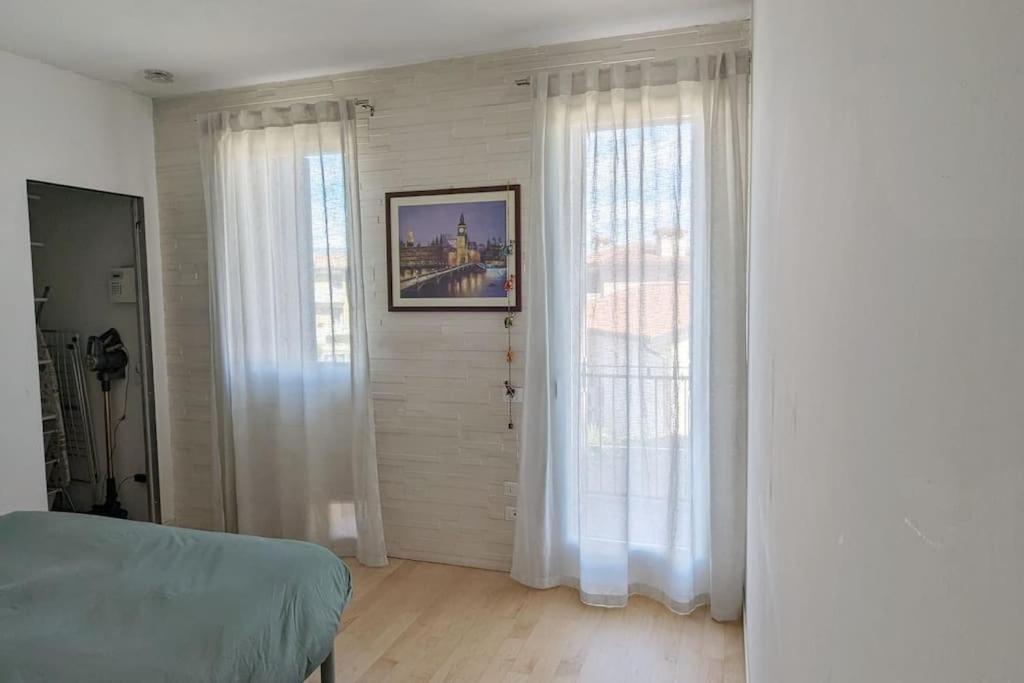 1 dormitorio con 2 ventanas grandes con cortinas blancas en Appartamento Ilaria, en Dueville