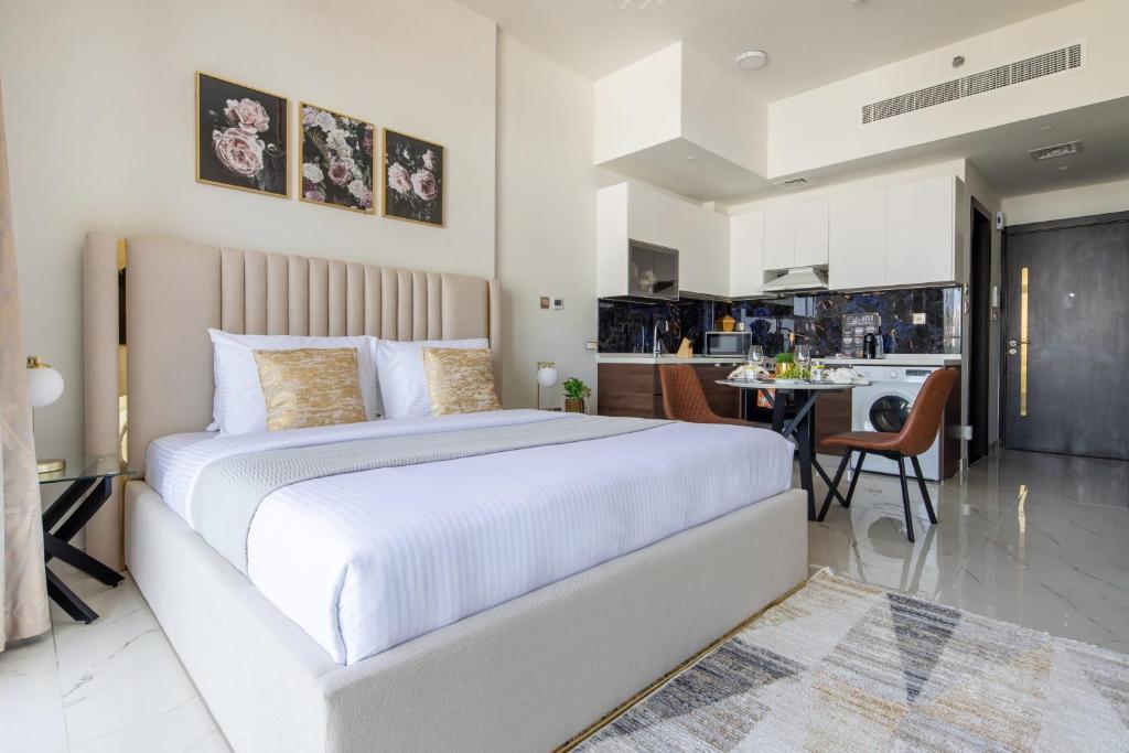 a bedroom with a large white bed and a kitchen at Frank Porter - Jwelz By Danube in Dubai