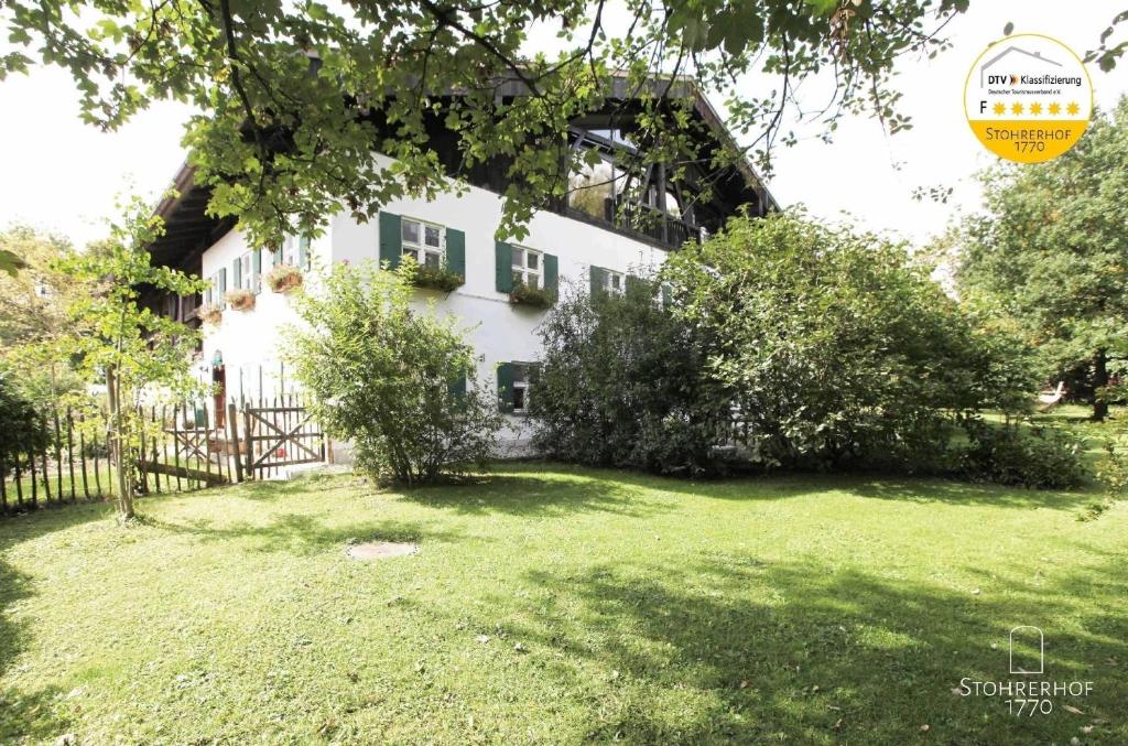 ein weißes Haus mit einem Zaun und einem Hof in der Unterkunft Ferienhaus in Riederau mit Großem Garten in Dießen am Ammersee
