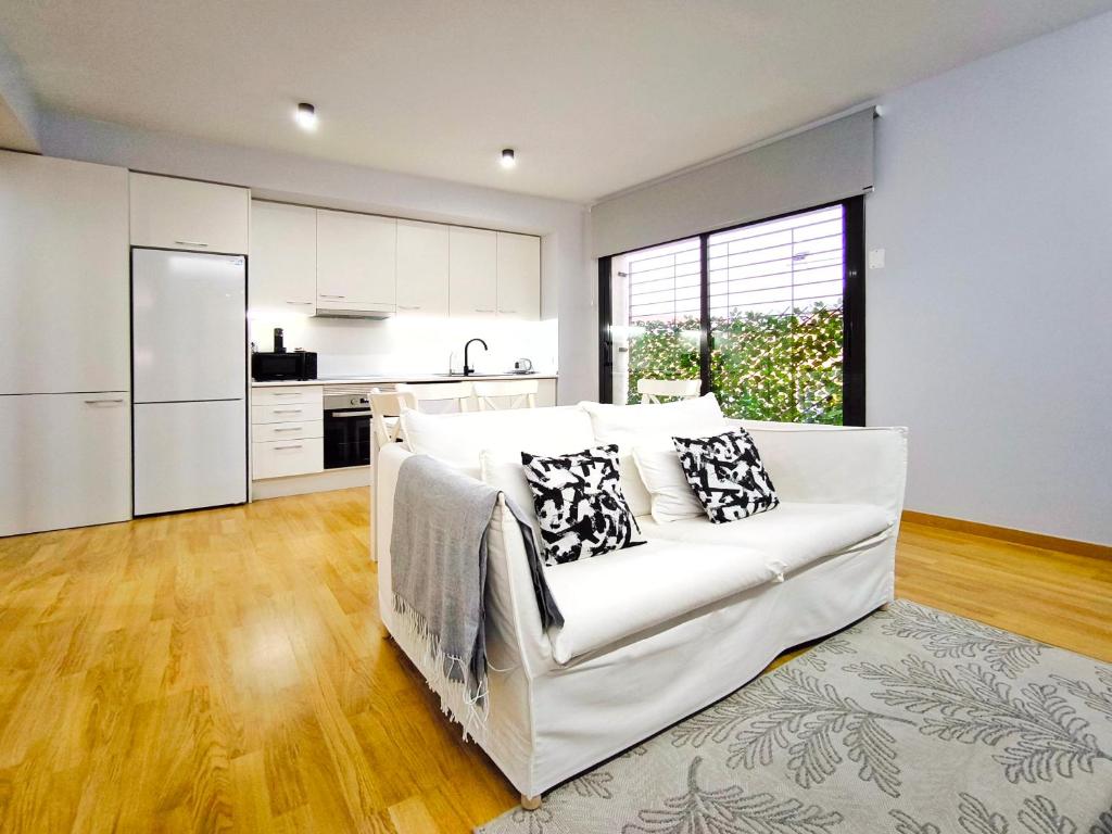 a living room with a white couch and a kitchen at Moderno apartamento tipo loft en Terrassa centro in Terrassa