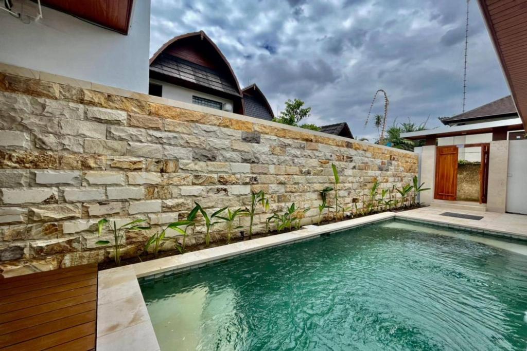 una piscina di fronte a un muro di mattoni di Belvilla 93823 Villa Gan Near Titi Batu Club Ubud ad Ubud