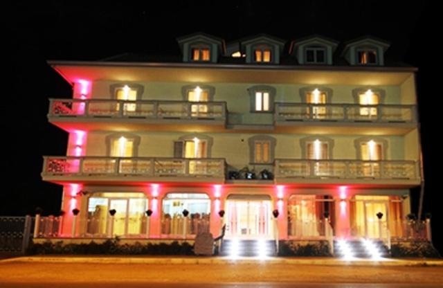 ノチェーラ・テリネーゼにあるPalace Hotel Una Nuova Stradaの赤いライトが映える白い大きな建物