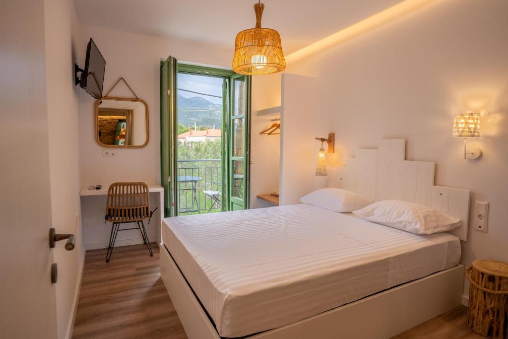 a white bedroom with a bed and a window at Olvio Suites in Kardamili