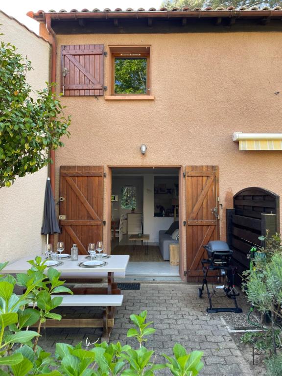 a patio with a table and chairs in front of a house at La Pinède - Séjour idéal entre plage et lac in Lacanau