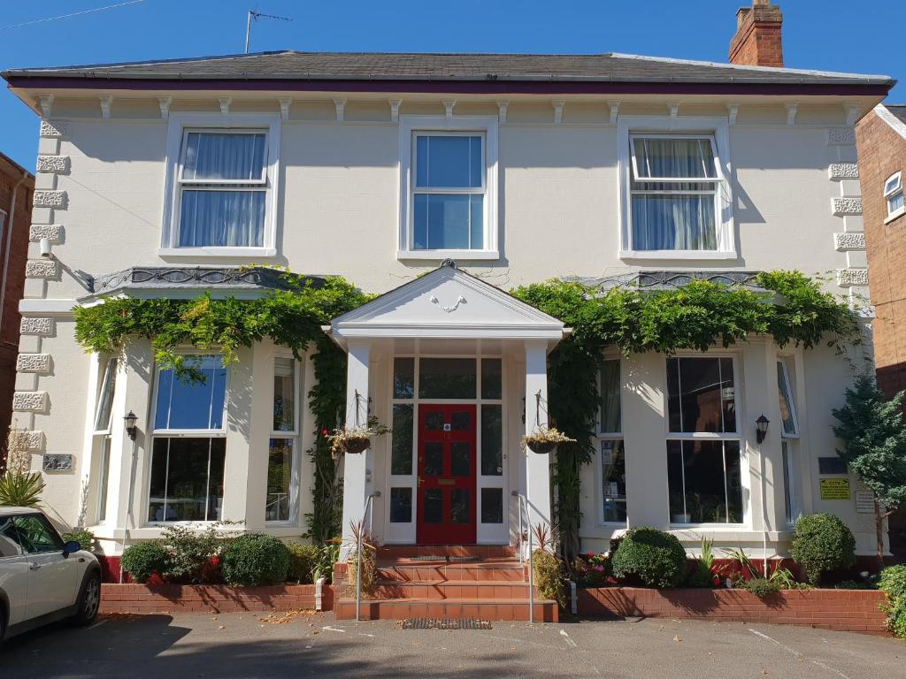 a white house with a red door at Victoria Park Lodge & Serviced Apartments in Leamington Spa
