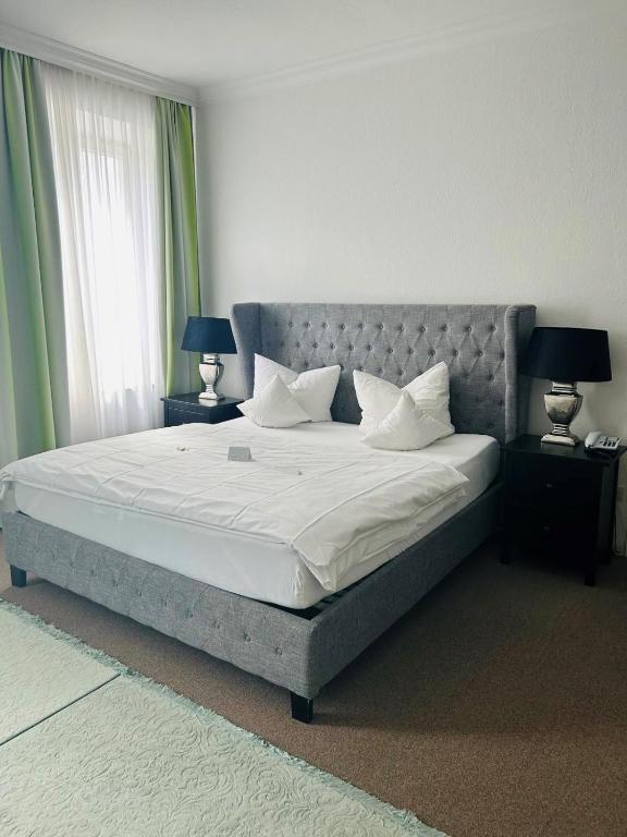 a bedroom with a large bed with two lamps on tables at Hotel Wendelstein in Rosenheim