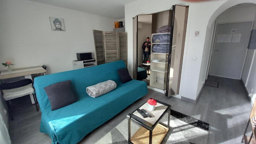 "La Dolce Vita" Studio cosy avec balcon في بو: غرفة معيشة مع أريكة زرقاء وطاولة