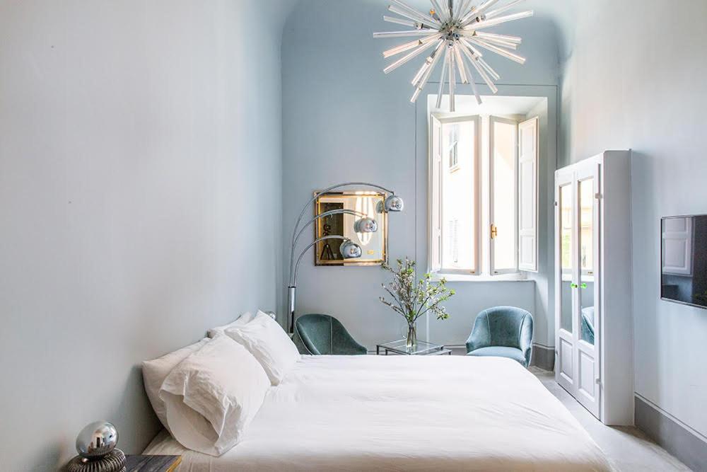 a bedroom with a large white bed and two chairs at Casa Iris in Orbetello