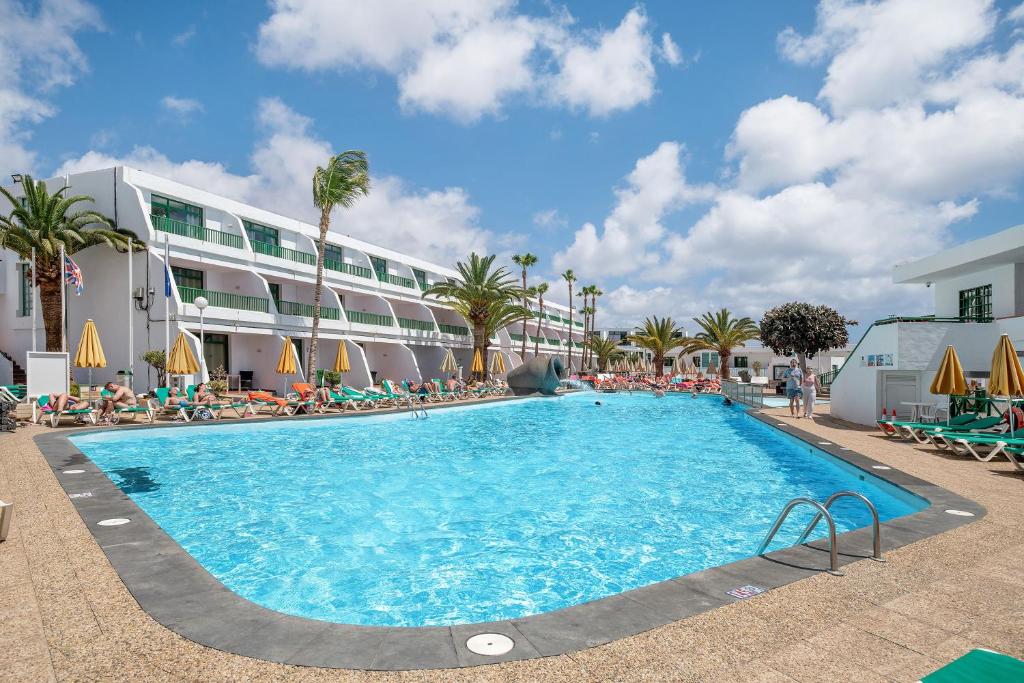 a large swimming pool in front of a hotel at Apartamento a 1 minuto de playa in Puerto del Carmen