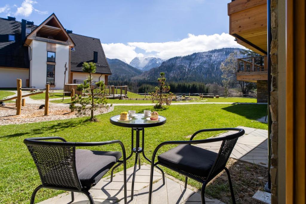 a patio with two chairs and a table in the grass at Podhalańskie Uroki by Apart Concept Podhale in Kościelisko