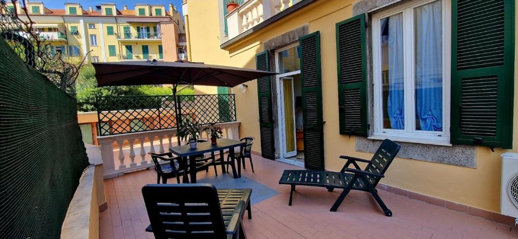 a patio with a table and chairs and an umbrella at Casa vacanza Teresita 300mt Mare in Imperia