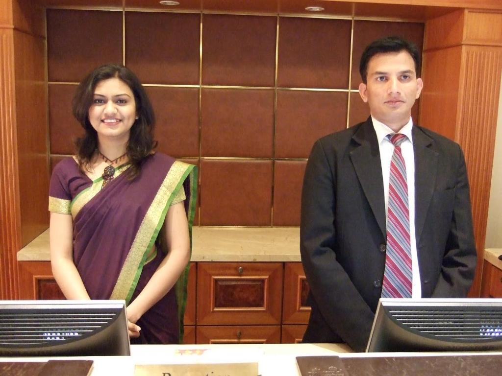 Un uomo e una donna in piedi davanti a una scrivania di CT ROOMS JAMAL ROAD by CLOVETREE a Patna