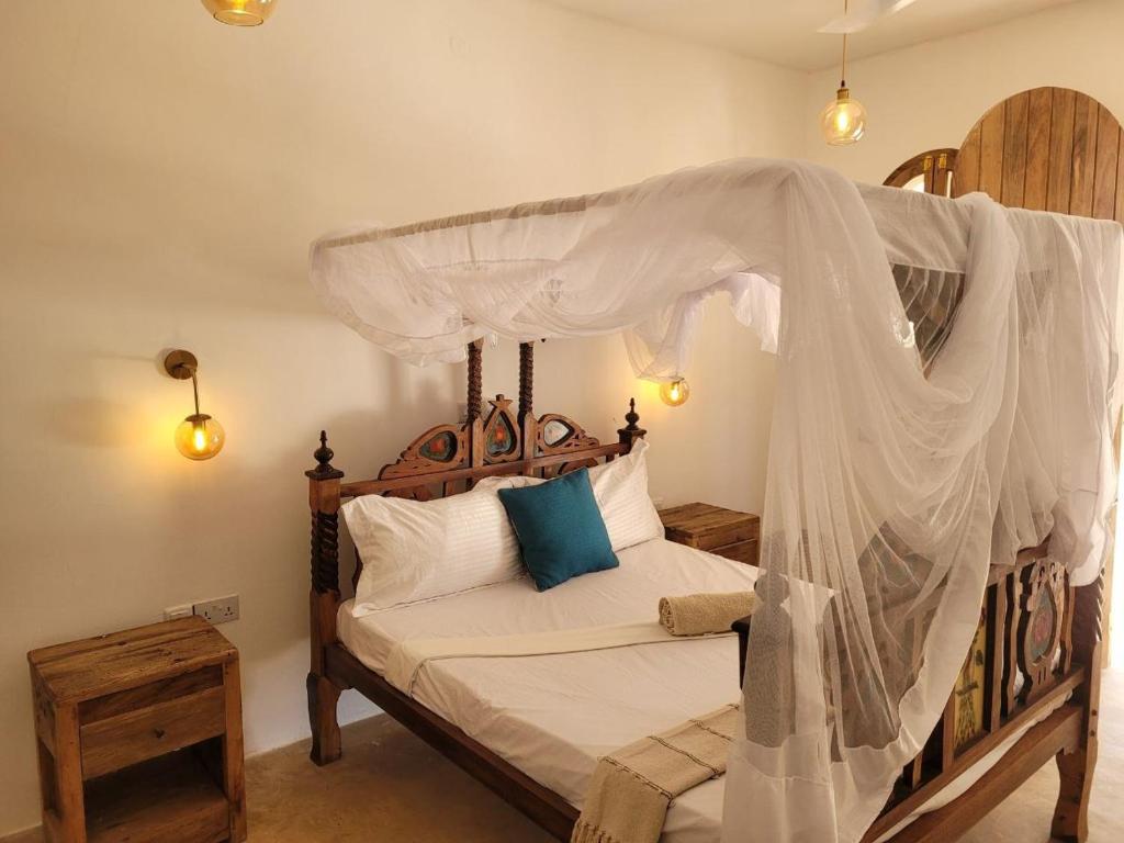 ein Schlafzimmer mit einem Himmelbett in der Unterkunft Coco Beach Hotel in Jambiani