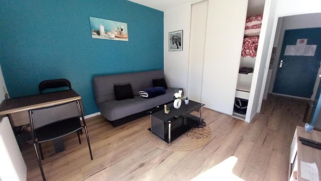 a living room with a couch and a table at Le petit Park-studio-terrasse- piscine-WIFI FIBRE in Pau