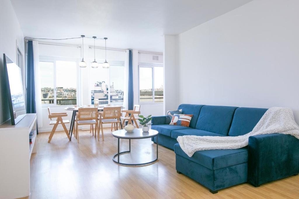 un salon avec un canapé bleu et une table dans l'établissement Majestic & Idyllic Parisian Flat - Champs-Elysées, à Paris