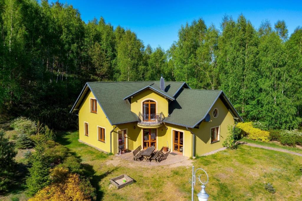 a yellow house with a black roof at Haus am See mit Sauna 