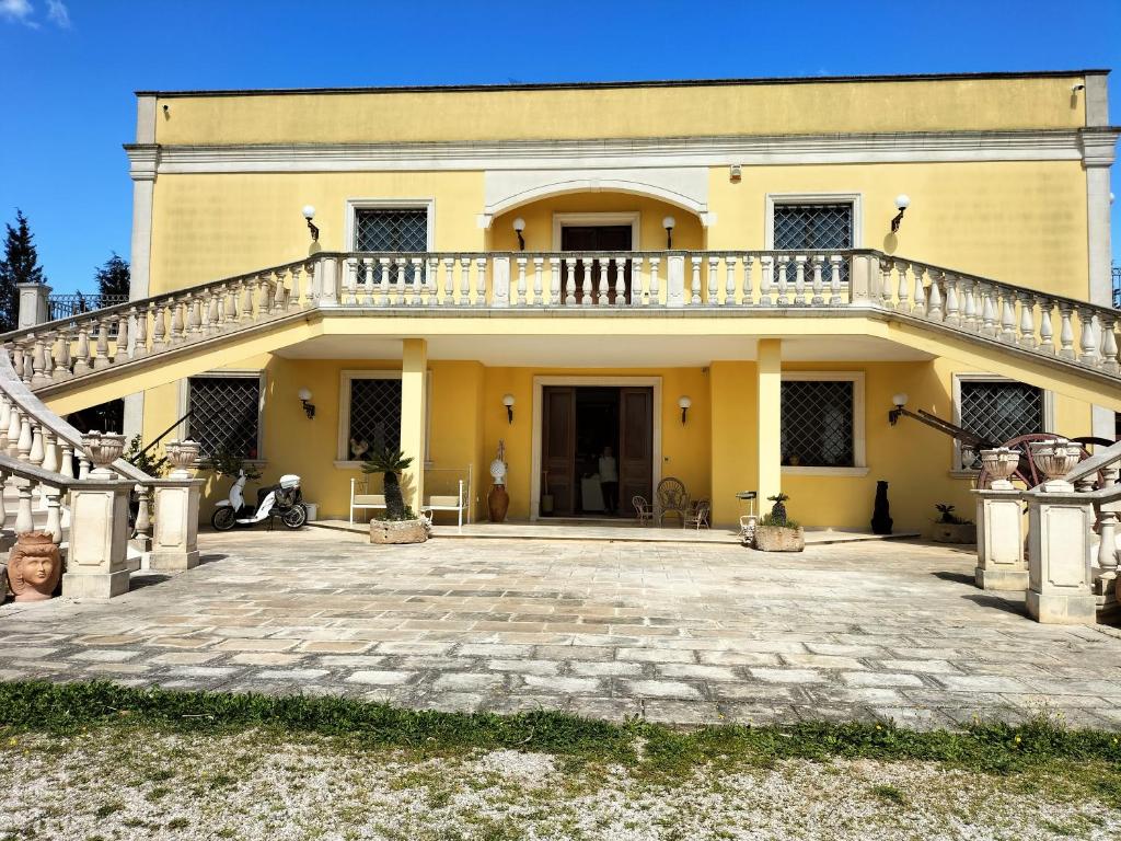 ein großes gelbes Haus mit einer großen Terrasse in der Unterkunft Villa Celea in Novoli