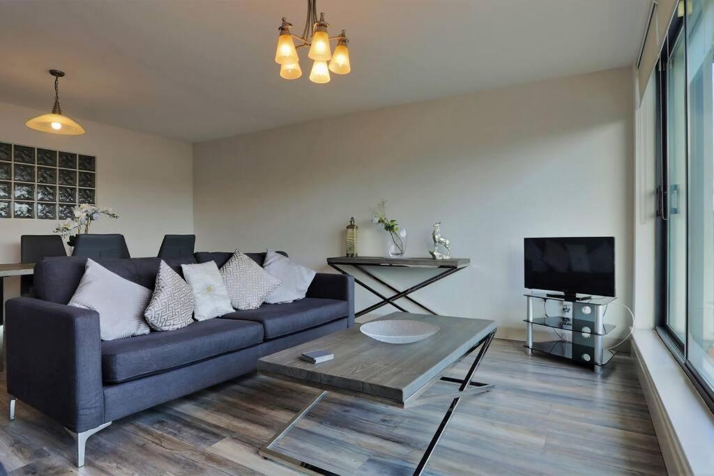 sala de estar con sofá azul y TV en Modern 3 bedroom apartment with city river views en Dublín