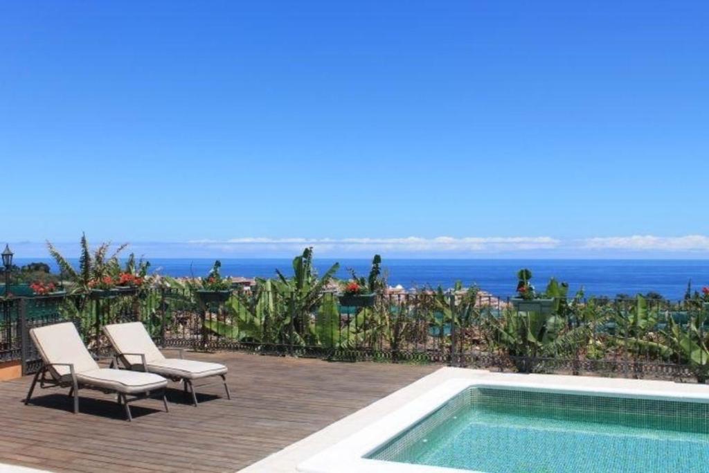 een zwembad met stoelen en uitzicht op de oceaan bij FInca Paraiso - ganzjährig geheizter Pool in Puerto de la Cruz