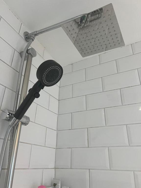 a shower head in a bathroom with white tiles at Single Unique Room For Professionals in Ealing