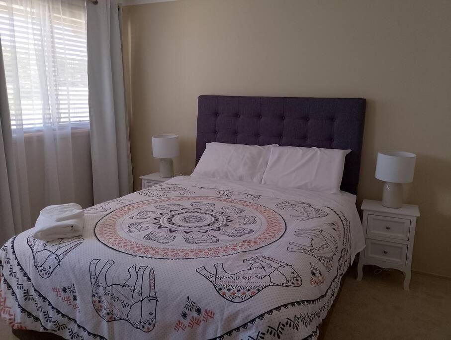 ein Schlafzimmer mit einem großen Bett mit gemusterter Decke in der Unterkunft Mansion @ the Coast in Albion Park